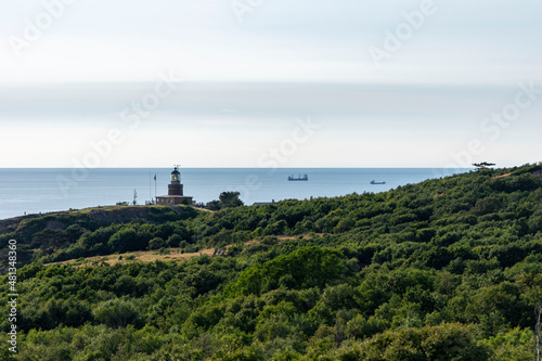 Kullaberg fyr, old lighthouse on the cliffs of Kullaberg naturreservat on the Swedish west coast. Lighthouse on the rocks viewing out into the baltic sea. Warm summer, high cliffs, deap ocean. Trees © Pavel