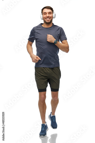 fitness, sport and healthy lifestyle concept - happy smiling man in headphones with smart watch or tracker running over white background