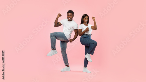Portrait of excited young black couple shaking clenched fists