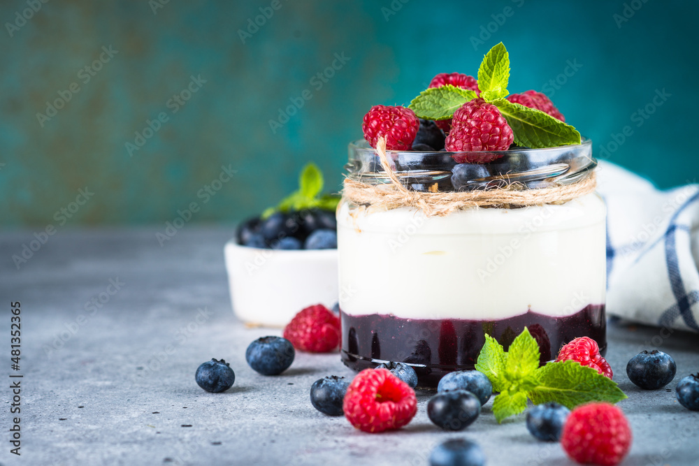 Parfait with cream or yogurt, jam and fresh berries in the glass jar. Close up. Parfait with cream or yogurt, jam and fresh berries in the glass jar. Close up.
