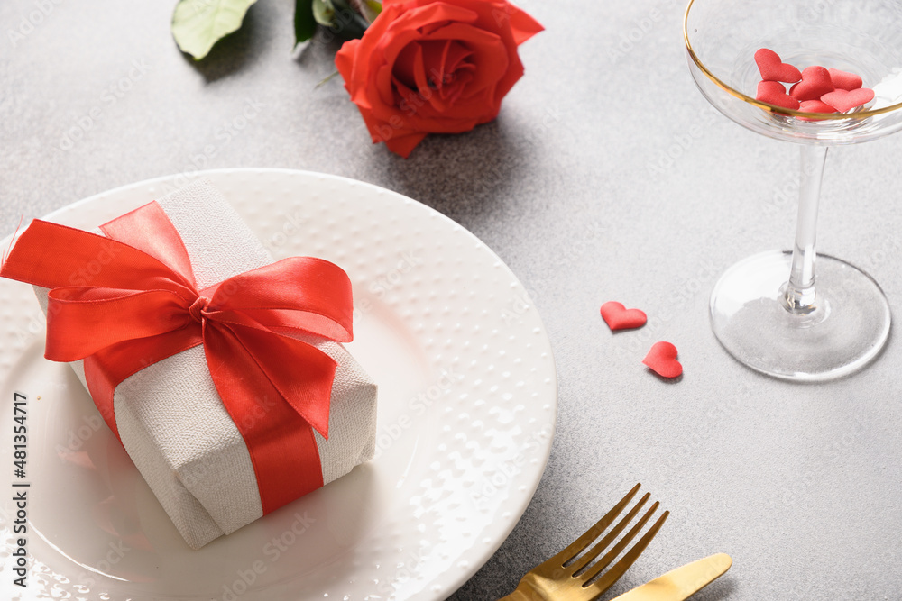 Valentine's day romantic dinner with red gift and red rose flower on gray background. Close up.