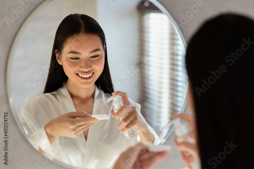 Pretty korean lady using cleansing milk, removing makeup photo