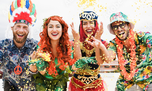 Happy dressed people celebrating at carnival party throwing confetti - Main focus on right man face photo