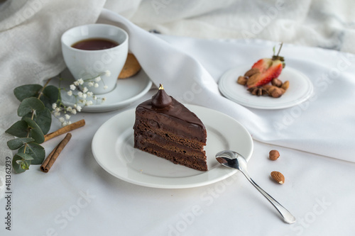 Slice of Triple Chocolate Ganache Cake and cup of tea on the table