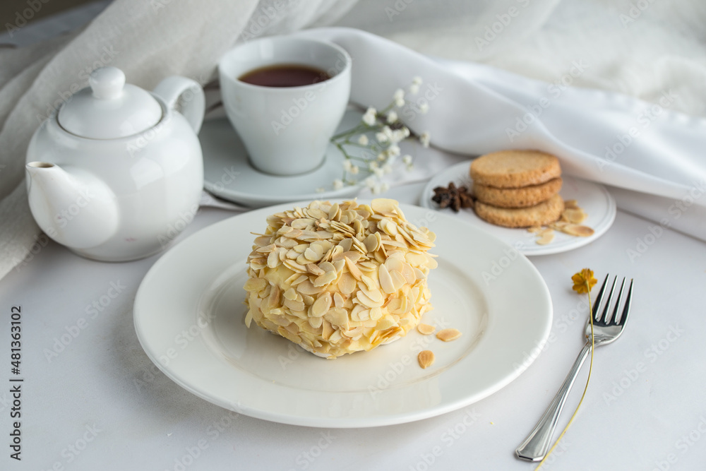 Whole cake decorated with almond flakes and cup of tea on the table Whole cake decorated with almond flakes and cup of tea on the table
