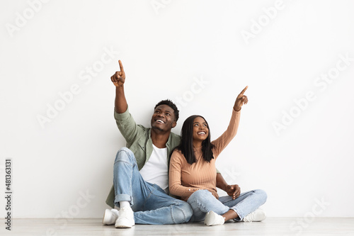 Loving african american couple pointing up at copy space