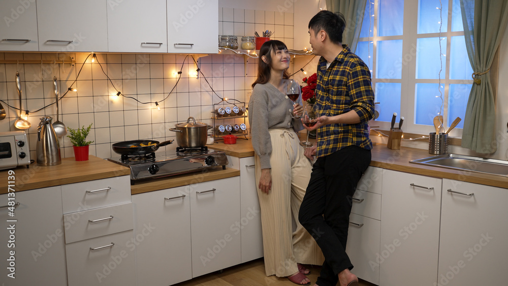 full length of smiling asian boyfriend and girlfriend toasting for valentine’s day while dating at home in a cozy decorated kitchen at night full length of smiling asian boyfriend and girlfriend toasting for valentine’s day while dating at home in a cozy decorated kitchen at night
