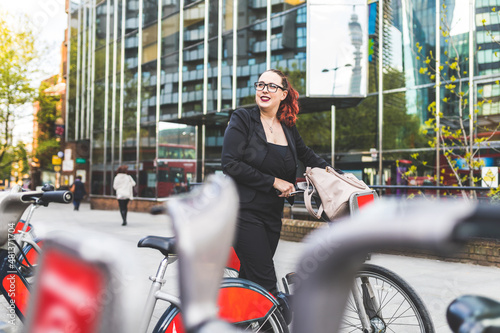 Young plus size business woman in the city using shared bike
