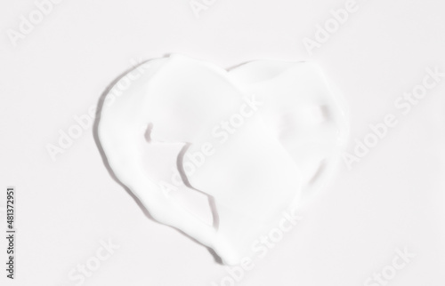Heart shape made of cream on a light gray background top view. Beauty product mockup with copy space.
