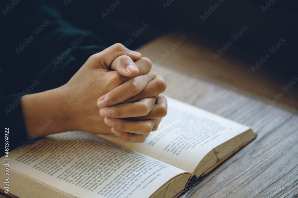 Naklejka premium Christian life crisis prayer to god. Women Pray for god blessing to wishing have a better life. Hands praying to god with the bible. believe in goodness. Holding hands in prayer on a wooden table.