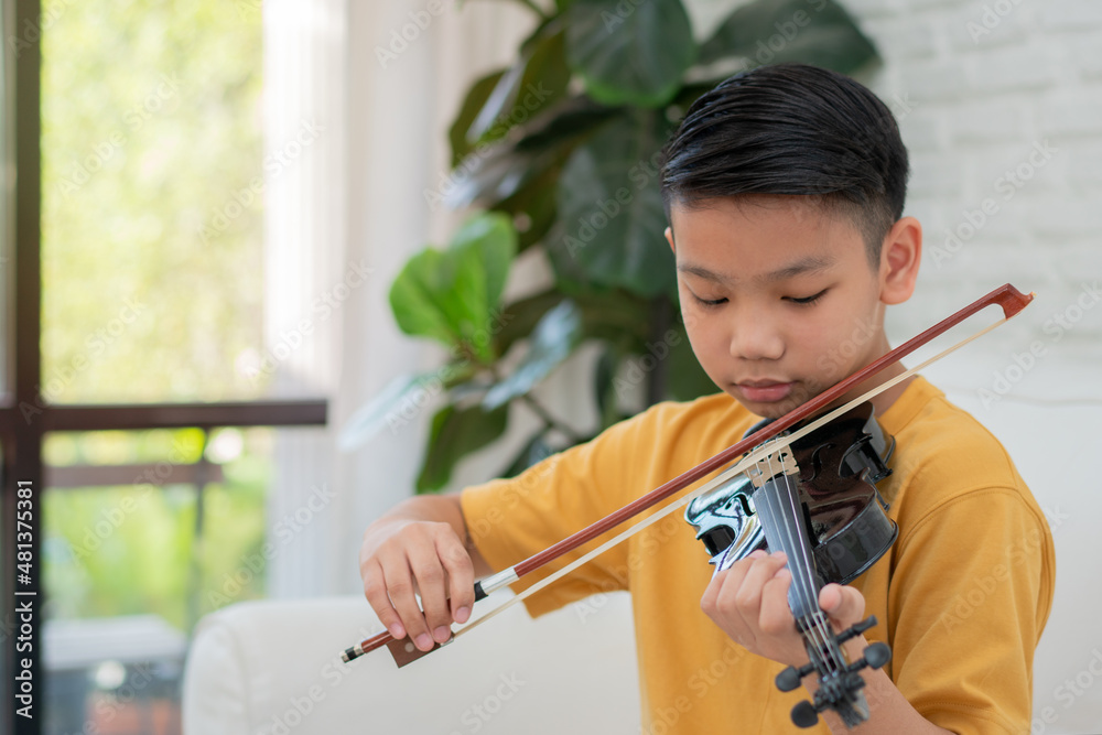 A Little Asian kid playing and practice violin musical string instrument against in home, Concept of Musical education, Inspiration, Teenager art school student. A Little Asian kid playing and practice violin musical string instrument against in home, Concept of Musical education, Inspiration, Teenager art school student.