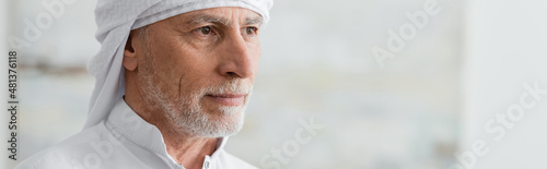 Fotografie, Obraz portrait of bearded muslim man in white turban looking away at home, banner