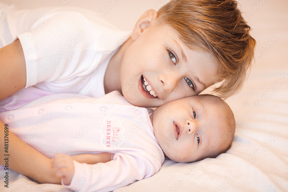 Little brother boy holding his newborn sister. Infant and child indoors. Little brother boy holding his newborn sister. Infant and child indoors.