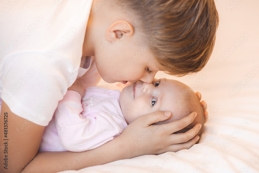 Little brother boy holding his newborn sister. Infant and child indoors. Little brother boy holding his newborn sister. Infant and child indoors.