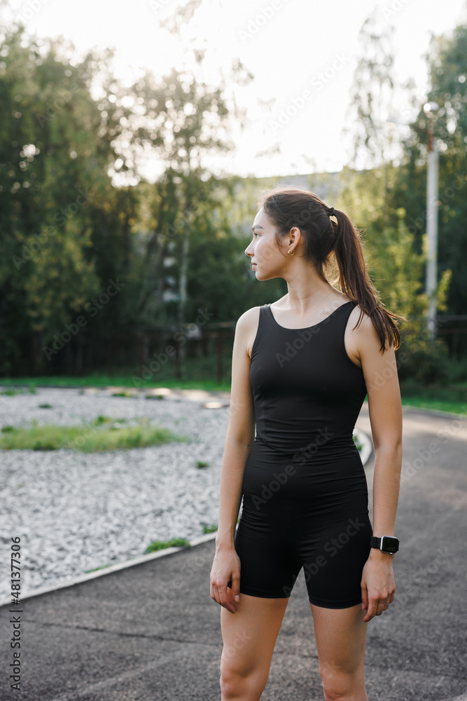 a Caucasian woman is resting after sports. A woman is sitting on the floor in a park, on a sports field. A tired young woman is resting after a run in the fresh air. a Caucasian woman is resting after sports. A woman is sitting on the floor in a park, on a sports field. A tired young woman is resting after a run in the fresh air.