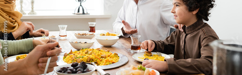 arabian boy smiling during dinner with muslim family at home  banner.