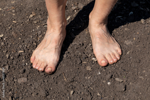 Barefoot woman stands on the raw soil with copy sace for your text © September