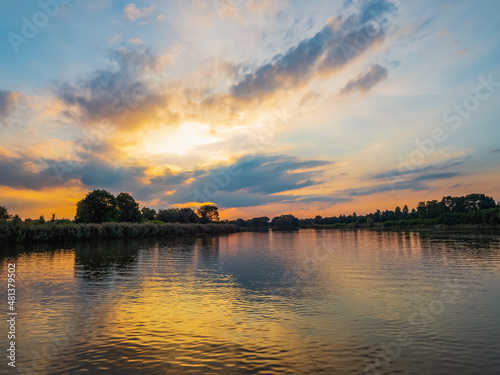 Evening sky with dramatic clouds over the river. Dramatic sunset in clouds and river. Nature landscape  reflection  blue cloudly sky and orange sunlight  landscape during sunset.