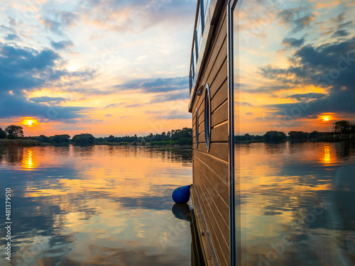 Fotografi Sunset behind houseboat on a river