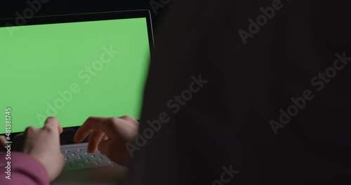 Green screen. The girl works at the laptop. View from behind.