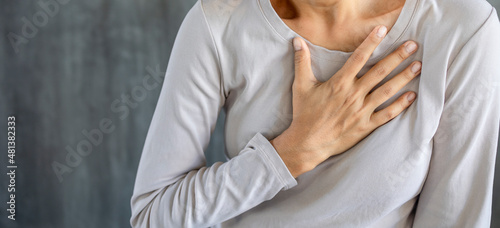 Woman suffers from chest pain and touches her heart area, heart attack photo