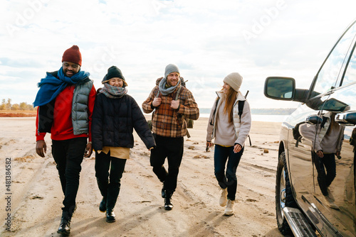 Multiracial friends laughing and hiking together during car trip photo