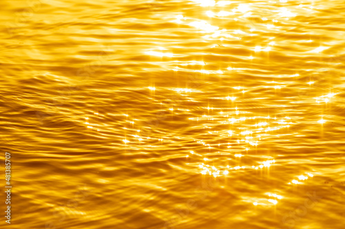 Abstract photo of surface water of sea or ocean at sunset time with golden light tone.