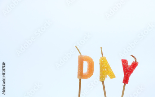 A candle with the word " Day " in bright colors against a white background.