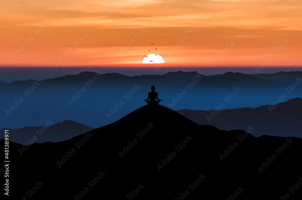 Silhouette of young male sitting practices yoga and meditating in lotus position alone on top of the mountain with beautiful sunrise and bird over the sky. He felt calm and happy.