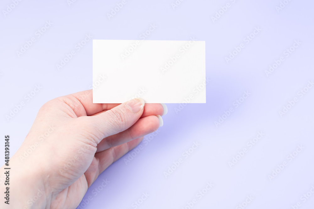 Female hand with a blank card isolated on purple background. One hands with empty white card. Female hand with a blank card isolated on purple background. One hands with empty white card.