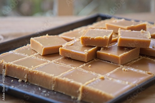 Homemade fudge squares on a baking sheet on an old wooden table