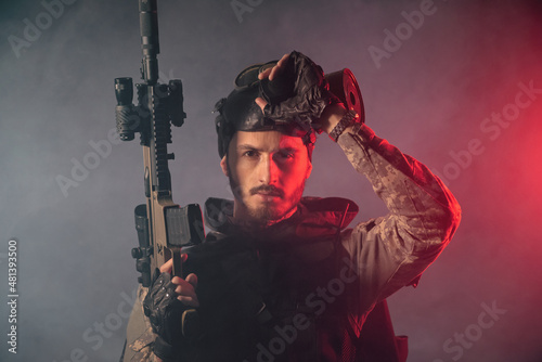 Soldier in gas mask with an airsoft rifle in the smoke concept.