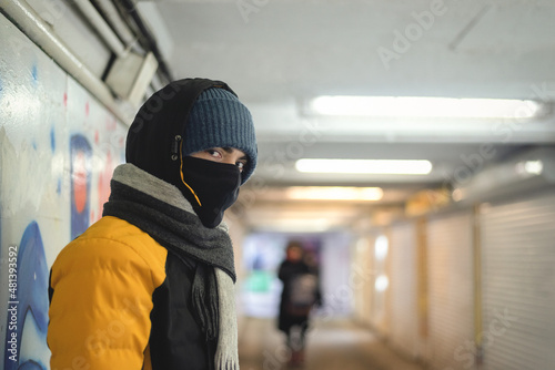 A young man in a protective mask stands in an underpass.