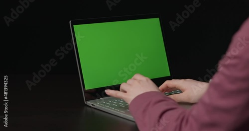 Green screen. The girl works at the laptop. View from behind.