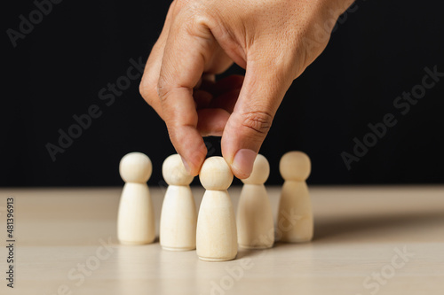 Wooden figures human was chosen leadership of teamwork. man's hands are select wooden puppet to devise strategies for appointing leaders. leadership of teamwork concept. photo