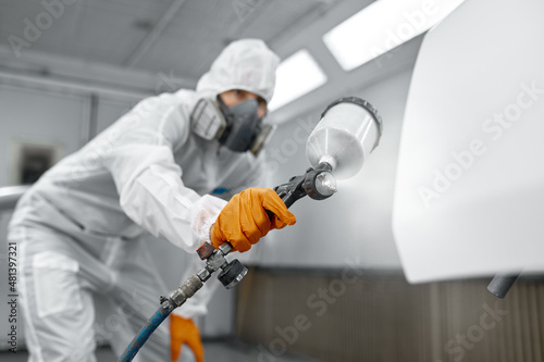 Painter in protective mask painting automobile door photo