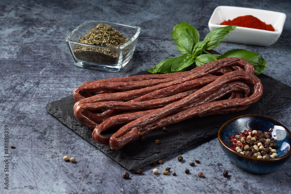 Hunting sausages on a dark background. Raw smoked hunting sausages on a dark background with spices