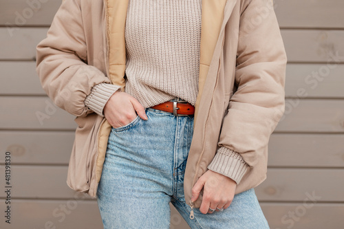 Canvas Print Woman in fashion outerwear with vintage beige knitted sweater, stylish blue jeans and jacket near a wooden wall