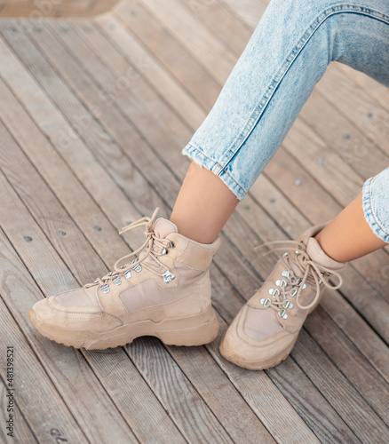 Fashionable girl in stylish blue jeans with beige winter boots with laces. Women's style and shoes