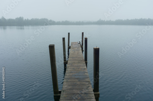 Narrow pier on the lake during morning fog