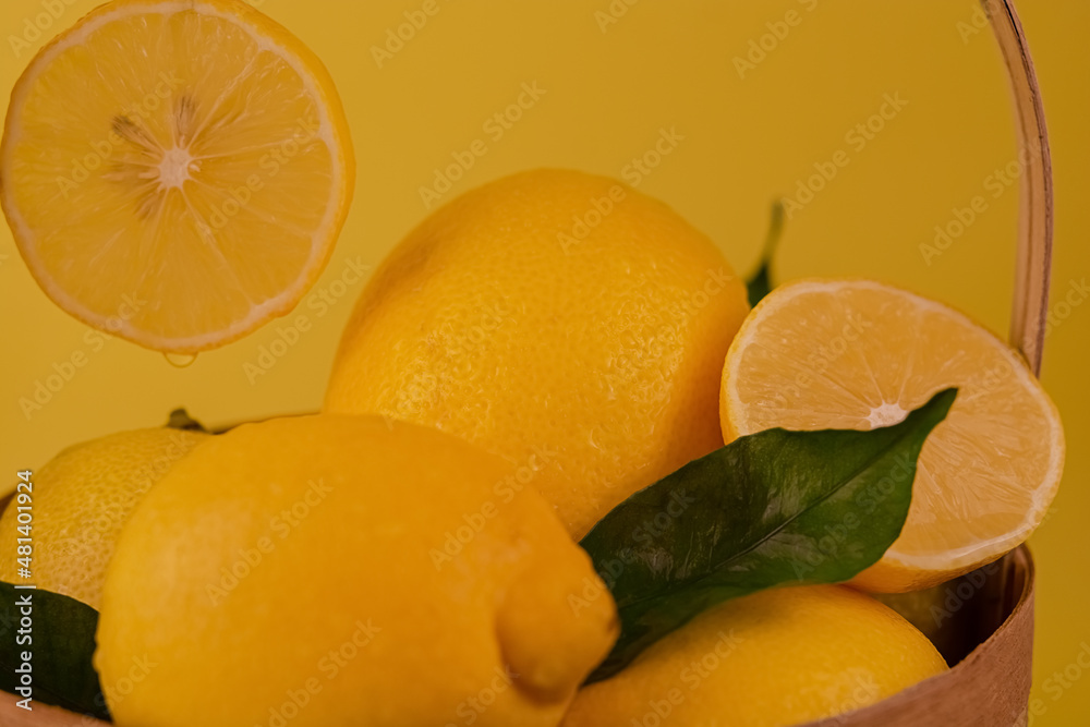 A group of lemons lie in a basket on a yellow background. Lemons on a yellow background.