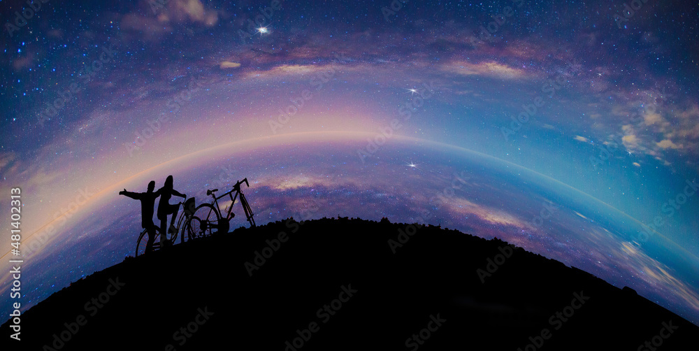 Silhouette Couple cycling on Panorama blue night sky milky way and star on dark background.