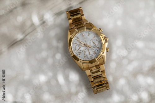 expensive beautiful ladies gold watch with a metal strap and a chronometer on a marble background with bokeh in light colors. Women's fashion accessory. Rich life concept, holiday gift, top view