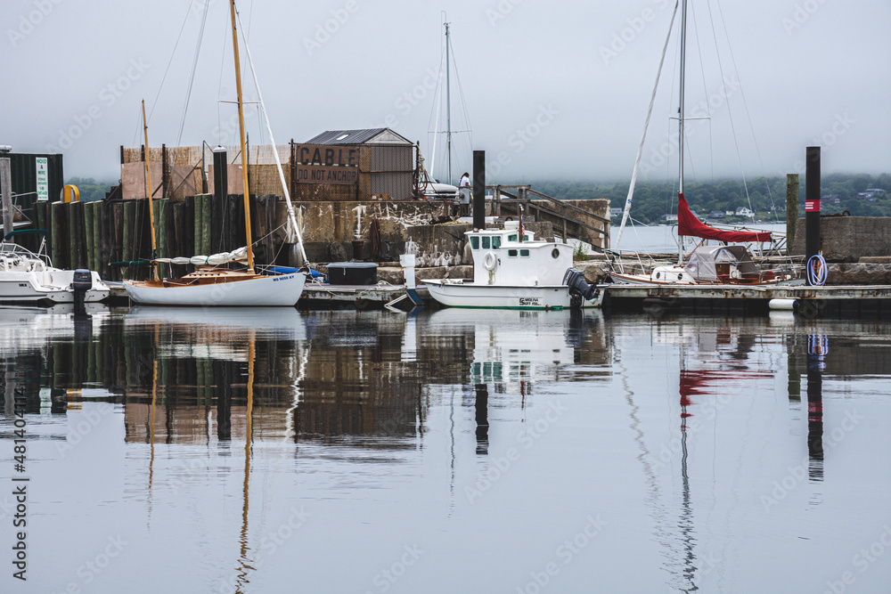 Small rustic harbor with sailboats in New England on cloudy day.