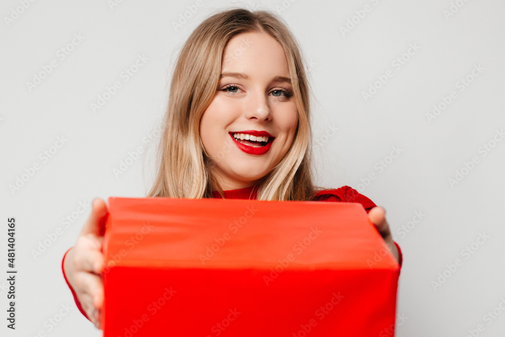 Cute blonde young woman is offering red Valentine gift box and is ready to talk about her feelings. Romance for Valentine's Day concept Cute blonde young woman is offering red Valentine gift box and is ready to talk about her feelings. Romance for Valentine's Day concept