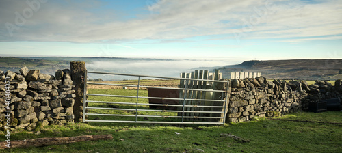 Let into a drystone wall, a 7 barred farm gate gives access to moorland grazing pasture © Fencewood studio