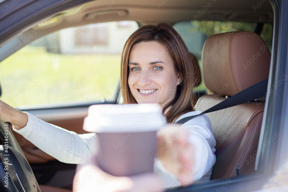 Courier hands over coffee to woman in car. Fast food and beverage delivery concept.