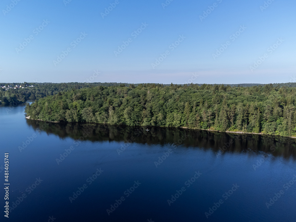 Aerial, drone photography of a sup board on a lake in summer time in Sweden. View of green trees and blue water and sky. Copy space and place for text.