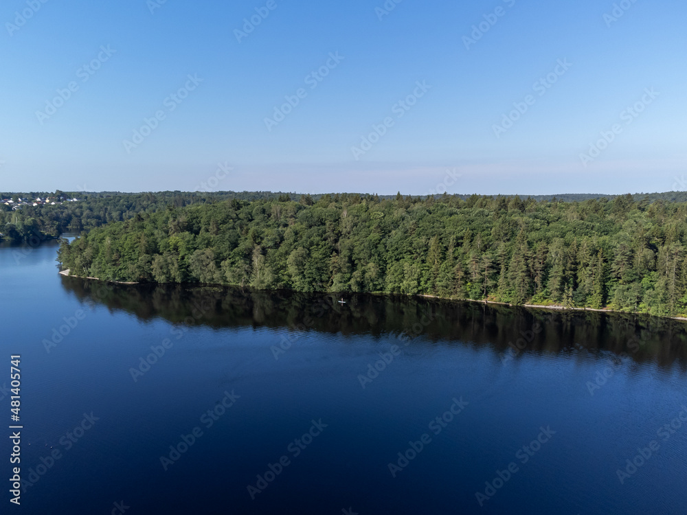 Aerial, drone photography of a sup board on a lake in summer time in Sweden. View of green trees and blue water and sky. Copy space and place for text. Aerial, drone photography of a sup board on a lake in summer time in Sweden. View of green trees and blue water and sky. Copy space and place for text.