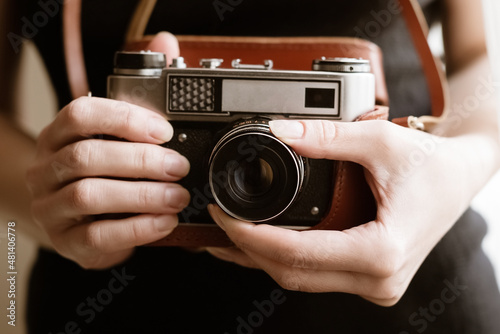 Woman holds old vintage film slr photo camera in leather cover in her hand